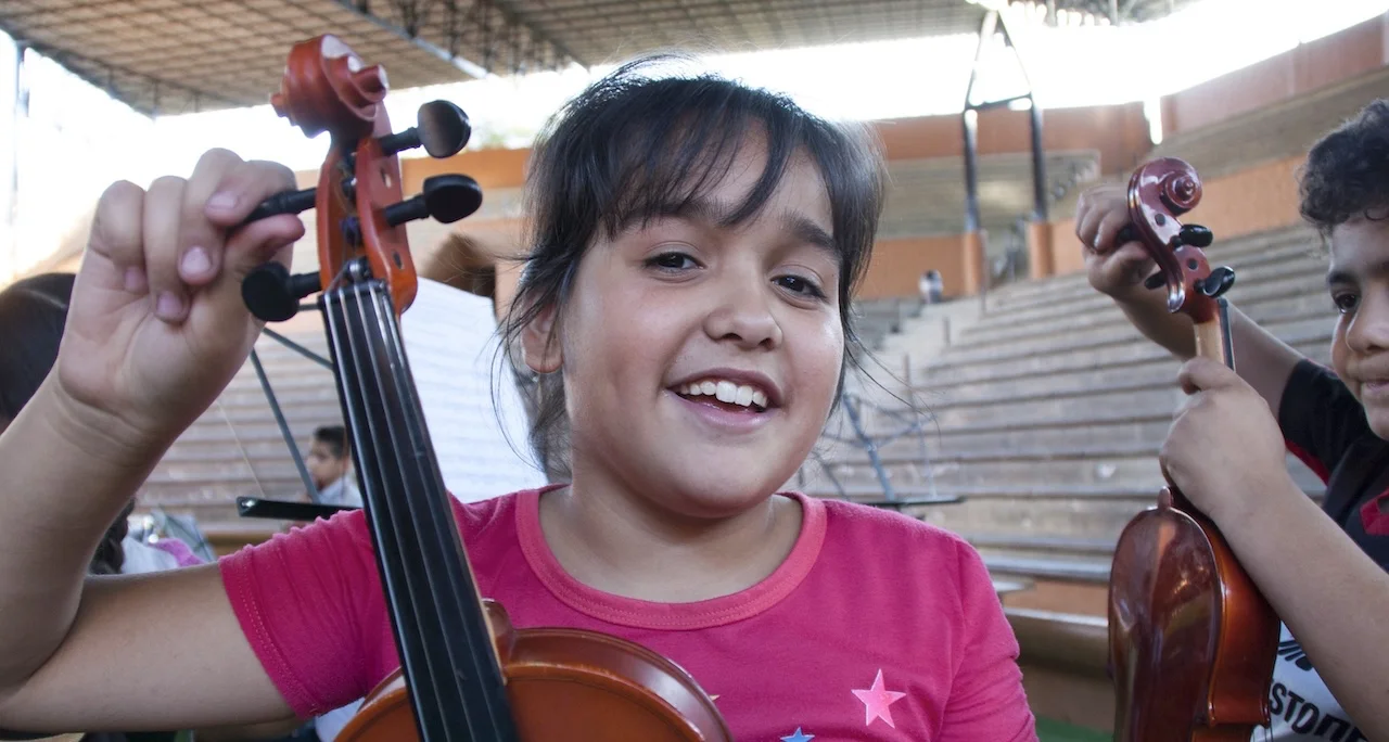 Niña contenta sosteniendo un violín